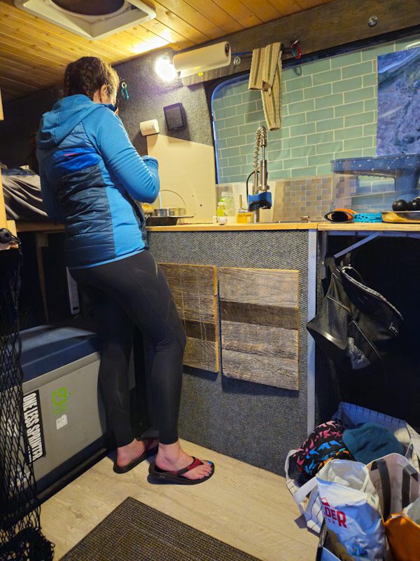Engearment reviewer Erin Trail maximizing leg recovery while cooking dinner in her campervan during a 2 day MTB camp